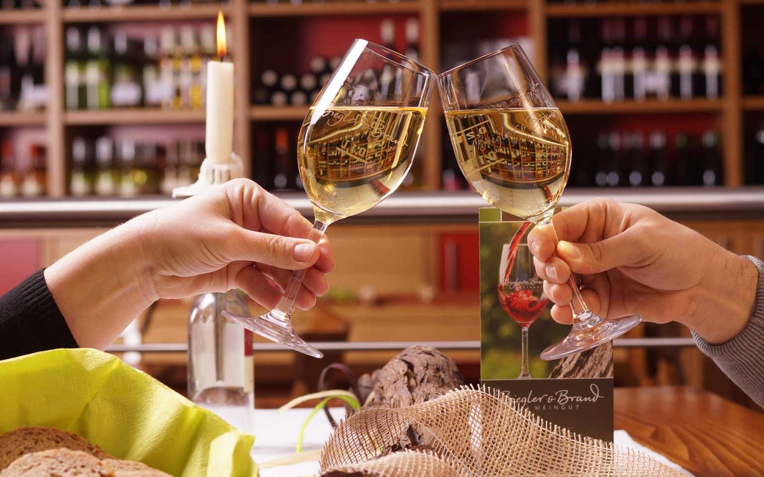 Weinprobe im Weinrestaurant & Vinothek Kaisergarten am eingedeckten Tische prosten sich zwei Personen mit zwei gefuellten Weissweinglaesern zu
